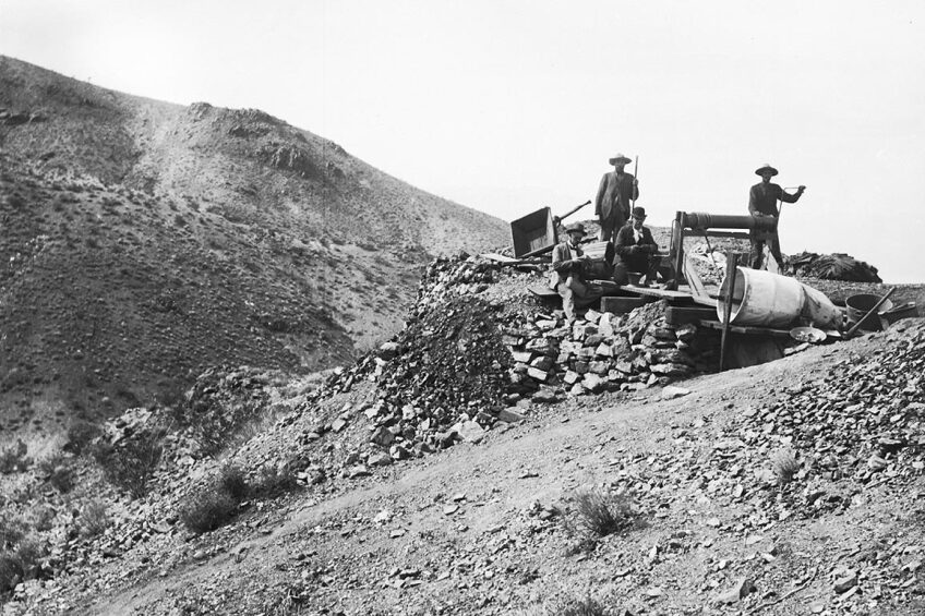 Four men at the Hard Cash Mine in Randsburg, CA photographed by Charles C. Pierce, ca. 1900. The man at the right is working a windlass. | Courtesy of USC Libraries and California Historical Society.