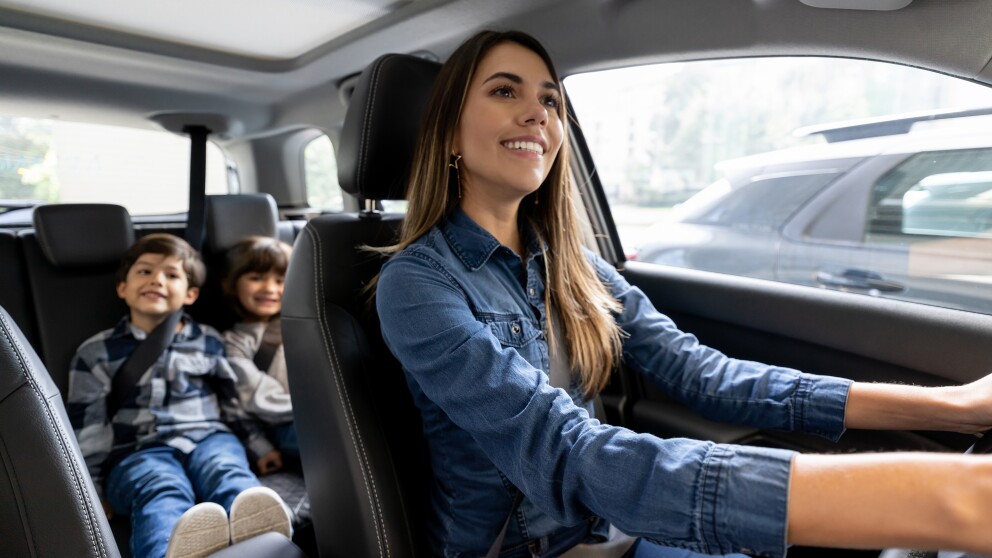 mom driving a car looks back at two little boys sitting in the backseat