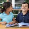 Two delighted kids enjoying a book at school. 