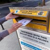 A woman places a ballot envelope into the slot of a Los Angeles County drop box