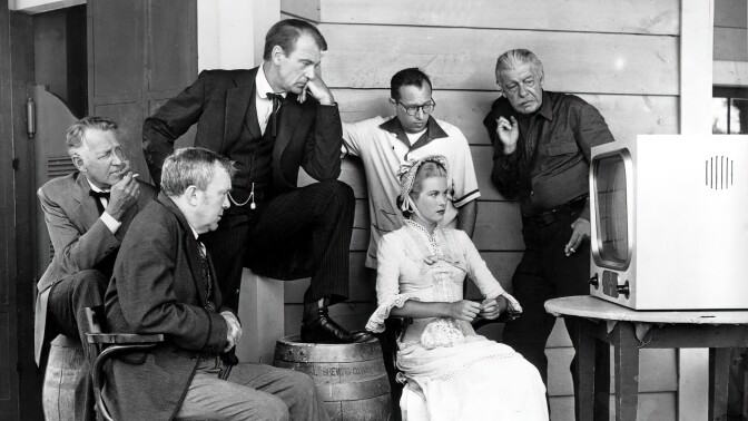 The cast of "high noon" gathers to see a computer screen on set.