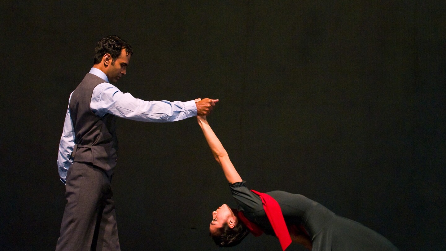 A barefoot man and woman dance together.