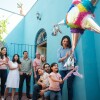 Happy mexican girl hitting piñata with stick and family looking